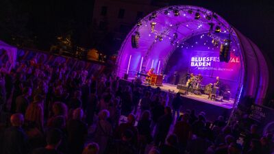 Beim Bluesfestival Baden (5400, Kanton Aargau) geniessen zahlreiche Besucher ein Konzert auf einer bunt beleuchteten Open-Air-Bühne in der Nacht.