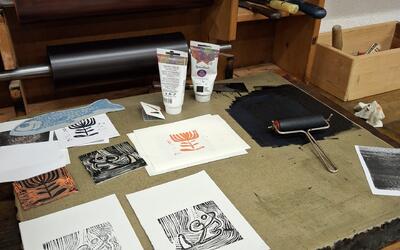 Auf einem Arbeitstisch des DruckLabor Horgen liegen Druckplatten, Papier, Farbe und Walzen bereit. Die Szene zeigt kreatives Arbeiten, handwerkliche Gestaltung und die traditionelle Drucktechnik in Horgen.
