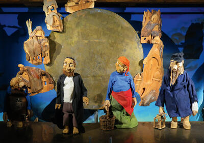 Im Figurentheater-Museum Herisau in 9100 Herisau im Kanton Appenzell-Ausserrhoden stehen kunstvoll gestaltete Figuren vor einer beleuchteten Kulisse aus Holzobjekten.