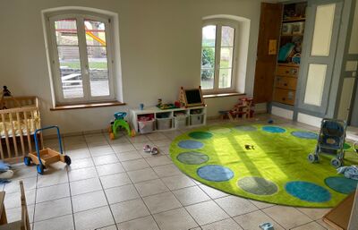 Ein heller Raum mit Spielteppich, Spielzeug und Kinderutensilien befindet sich in Kerzers (3210, Kanton Freiburg) und zeigt eine Kinderbetreuung.