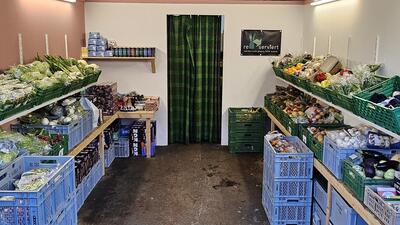 In einem Lagerraum in Pfäffikon (8330, Kanton Zürich) sind gerettetes Gemüse, Früchte und weitere Lebensmittel übersichtlich in Kisten und Regalen angeordnet.
