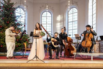 Bei einem Konzert des Vereins Stretta Concerts musizieren in Brugg (5200, Kanton Aargau) eine Sängerin und vier Instrumentalisten vor einem geschmückten Weihnachtsbaum.