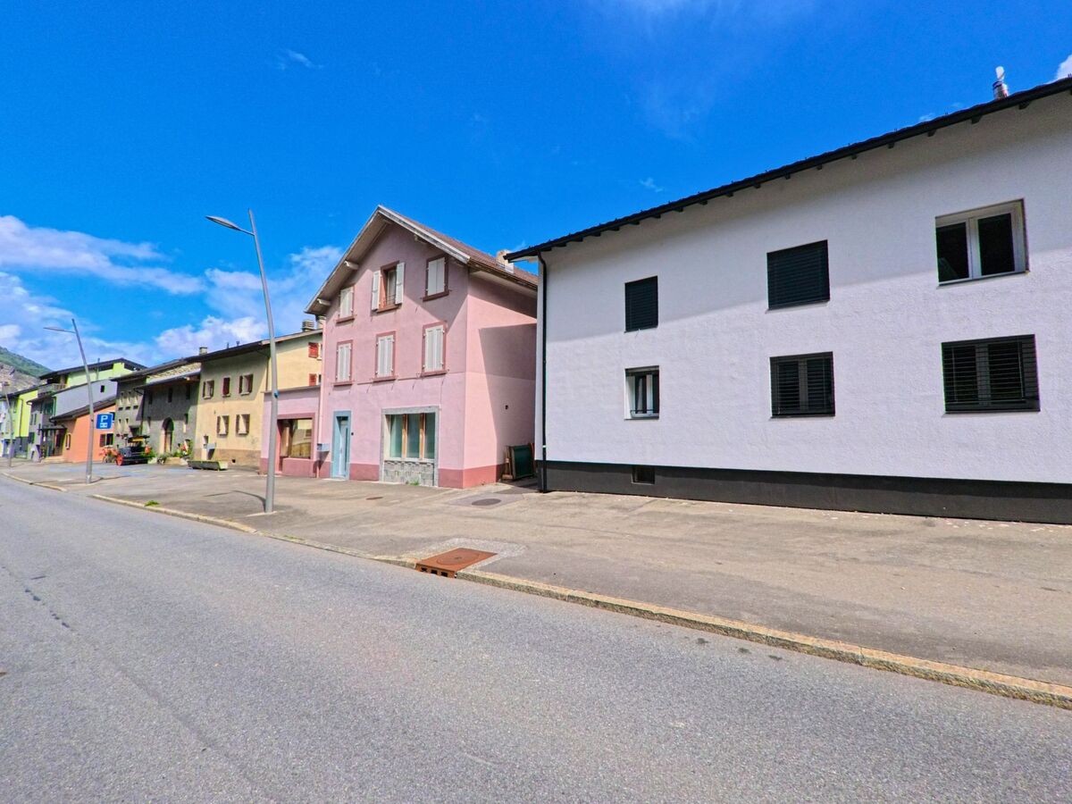 In Vernayaz (1904, Kanton Wallis) stehen farbig gestrichene Wohnhaeuser mit einfachen Fassaden entlang einer breiten Strasse.