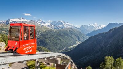 Die rote Standseilbahn VerticAlp Emosson in Le Châtelard VS (1925, Kanton Wallis) fährt hoch über dem Tal mit eindrucksvoller Sicht auf die umliegenden Berge und Gletscher.