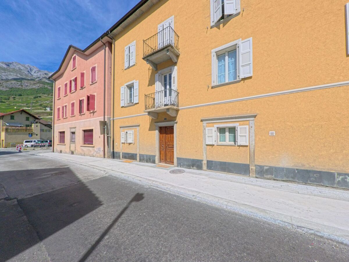 In Vetroz (1963, Kanton Wallis) saeumen bunte Wohnhaeuser mit Fensterlaeden und Balkonen eine schmale Strasse.