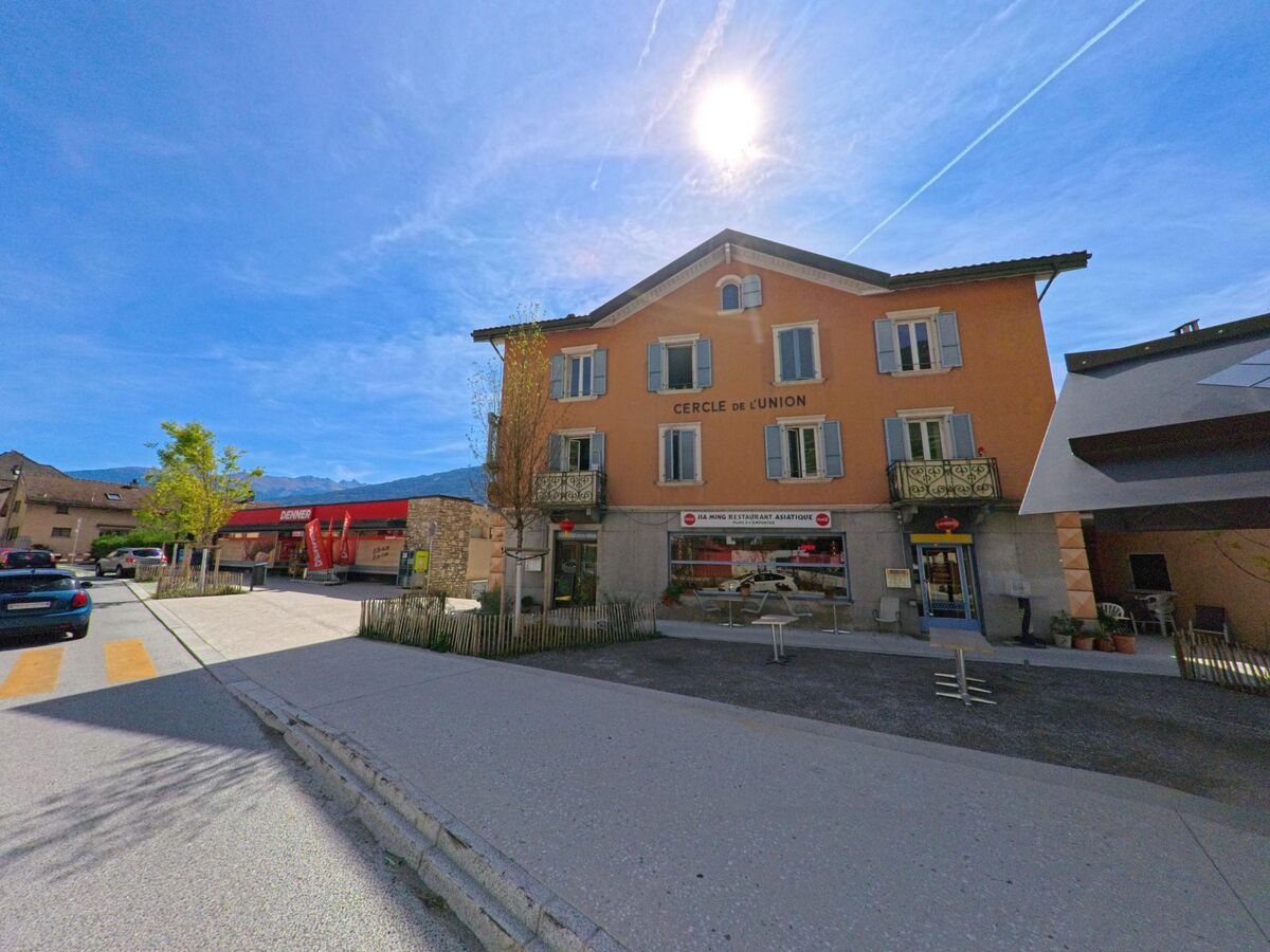 In Vetroz (1963, Kanton Wallis) steht ein markantes Gebaeude mit Restaurant und Laeden an einer kleinen Strasse im Zentrum.