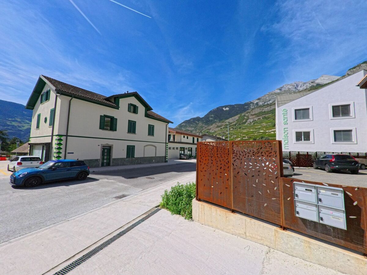 In Vetroz (1963, Kanton Wallis) stehen traditionelle und moderne Gebaeude nebeneinander, eingerahmt von den Bergen im Hintergrund.