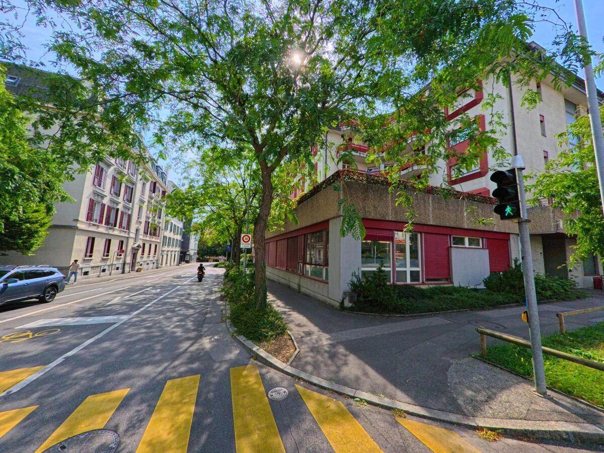 Baumgesaeumte Strasse in Vevey (1800, Kanton Waadt) mit Wohnhaeusern und einem Eckgebaeude mit roten Fensterlaeden.
