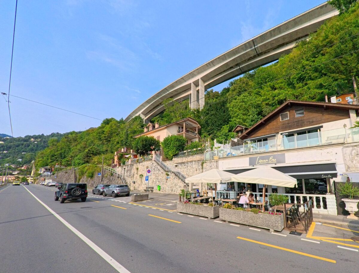 In Veytaux (1820, Kanton Waadt) liegt ein kleines Café mit Terrasse unterhalb einer grossen Autobahnbrücke, umgeben von grünen Hängen und Wohnhäusern.
