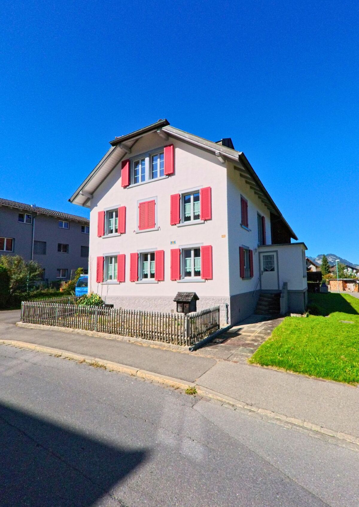 Ein helles Wohnhaus mit roten Fensterlaeden steht in Vilters-Wangs (7324, Kanton St. Gallen) an einer ruhigen Nebenstrasse mit kleinem Vorgarten.