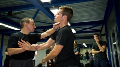 In Horgen (8810, Kanton Zürich) übt ein Lehrer mit einem Schüler in einer Trainingshalle eine Technik des Ving Tsun Kung Fu, während andere Teilnehmer im Hintergrund das Training beobachten.