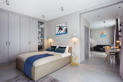 Ein modernes Apartment der VISIONAPARTMENTS in Saint-Sulpice (1025, Kanton Waadt) verfügt über ein helles Schlafzimmer mit integriertem Arbeitsbereich und schlichter, eleganter Einrichtung.