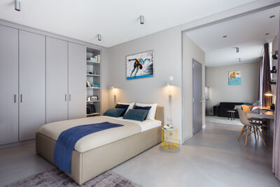 Ein modernes Apartment der VISIONAPARTMENTS in Saint-Sulpice (1025, Kanton Waadt) verfügt über ein helles Schlafzimmer mit integriertem Arbeitsbereich und schlichter, eleganter Einrichtung.