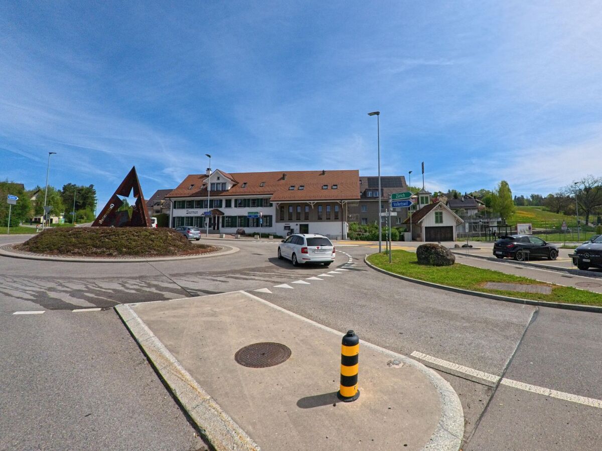 In Volketswil (8605 im Kanton Zürich) liegt ein Kreisverkehr mit sternförmiger Skulptur vor dem Gebäude des Restaurants Sternen und angrenzenden Parkplätzen.