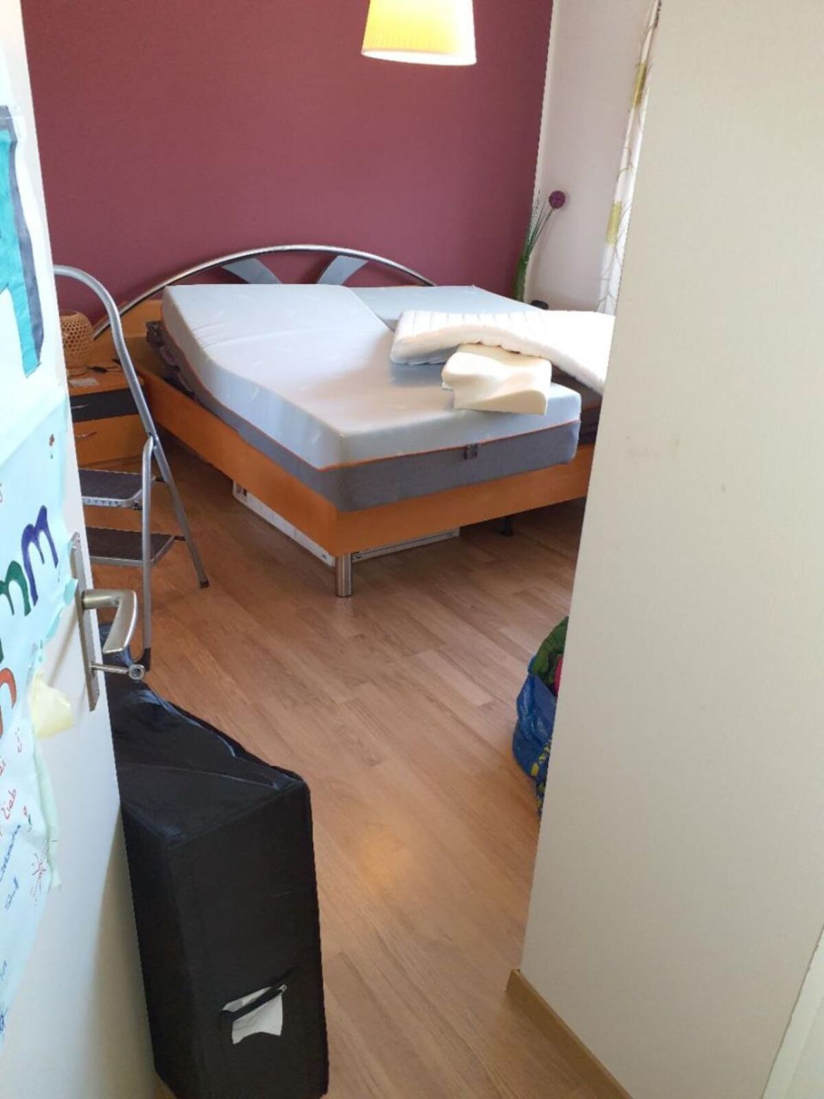In einem Wohnhaus in Wädenswil (8824, Kanton Zürich) zeigt das Bild ein Schlafzimmer mit aufgestellter Matratze, Holzfussboden und violett gestrichener Wand.