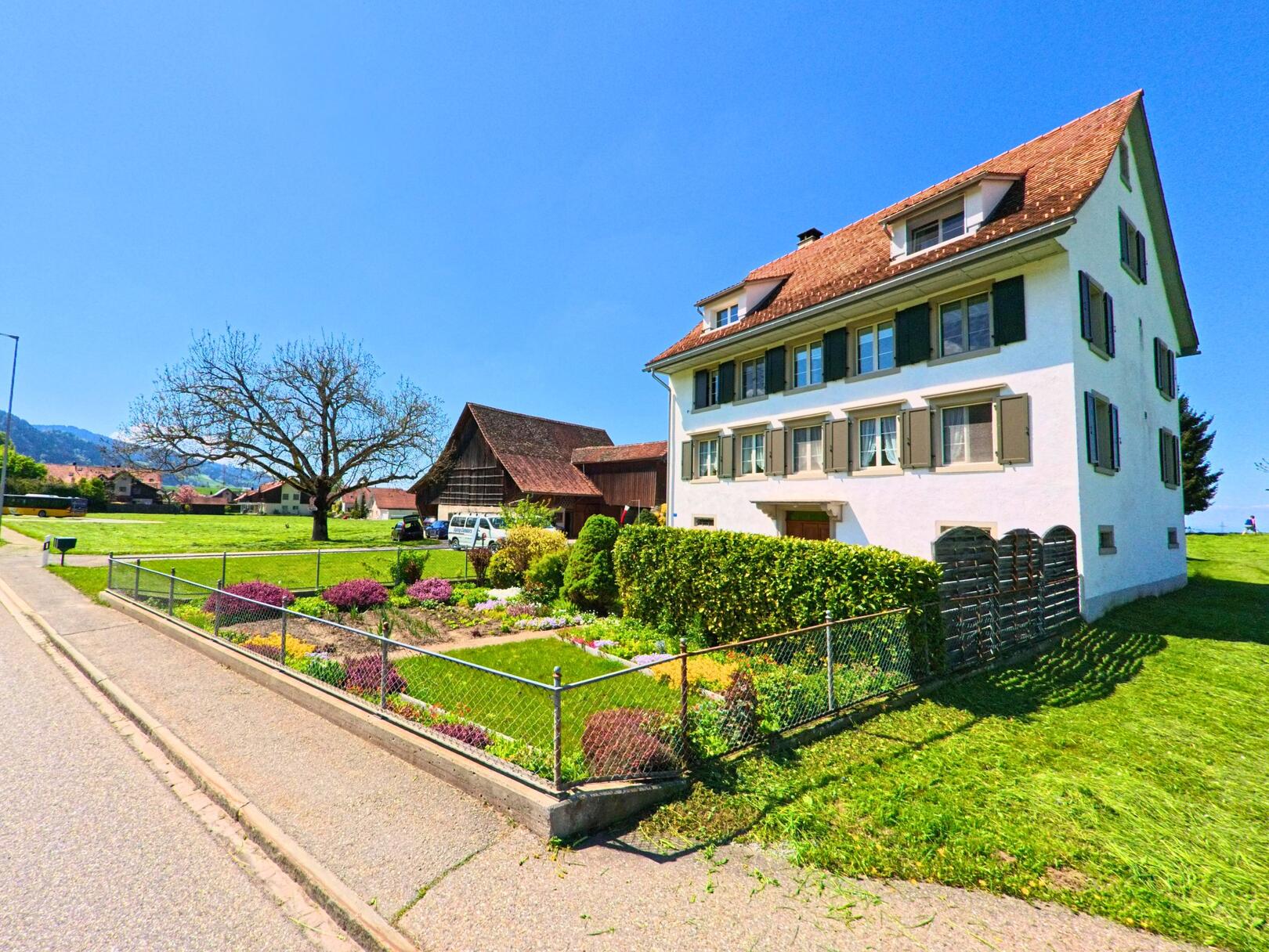 Am sonnigen Ortsrand von Wädenswil (8825 im Kanton Zürich) steht ein traditionelles Wohnhaus mit gepflegtem Garten neben einer weiten Wiese.