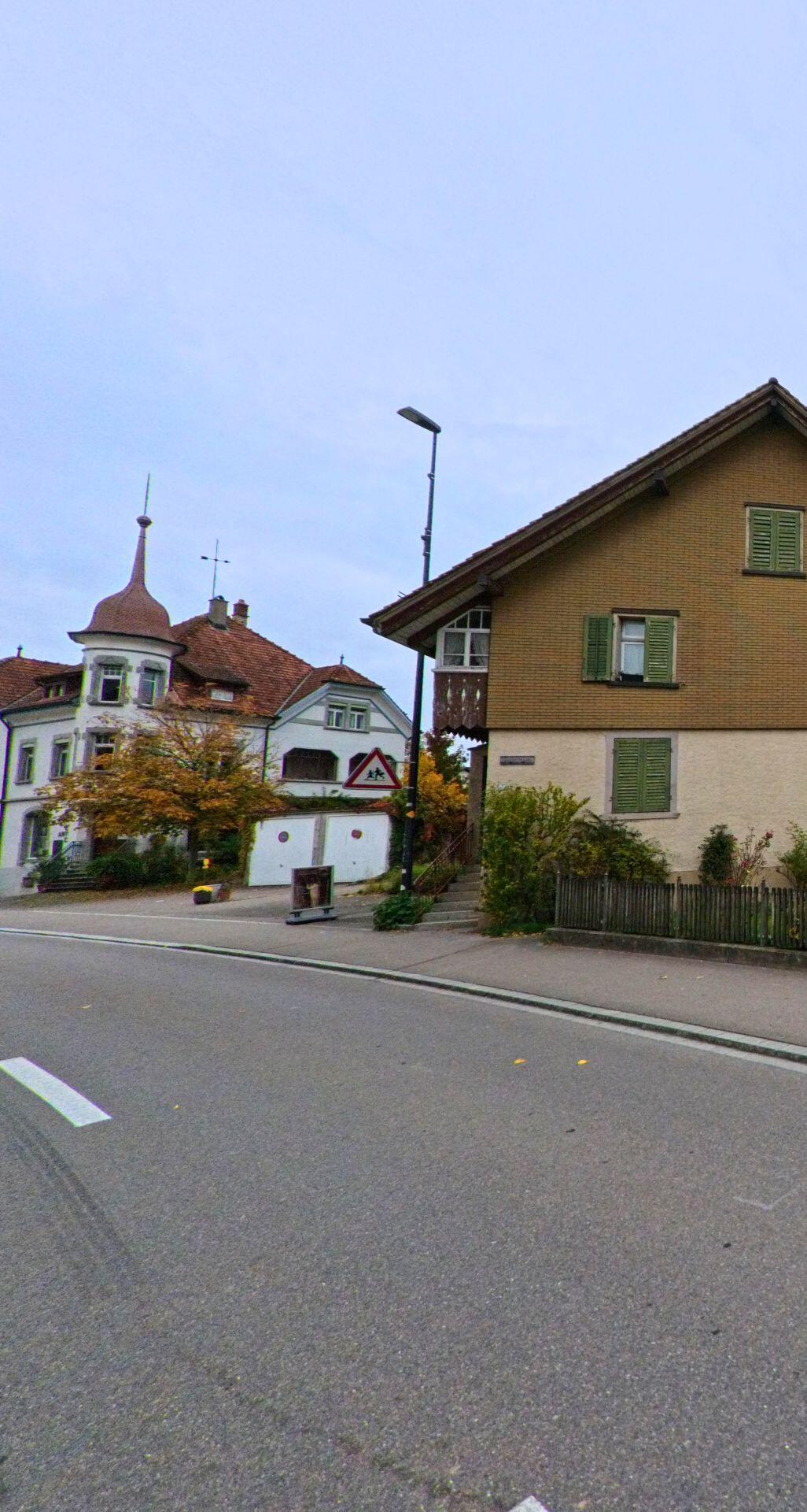 Entlang einer Strasse mit historischen Wohnhäusern und einem markanten Eckturm prägt traditionelle Architektur das Ortsbild von Wängi (9545, Kanton Thurgau) im Herbst.