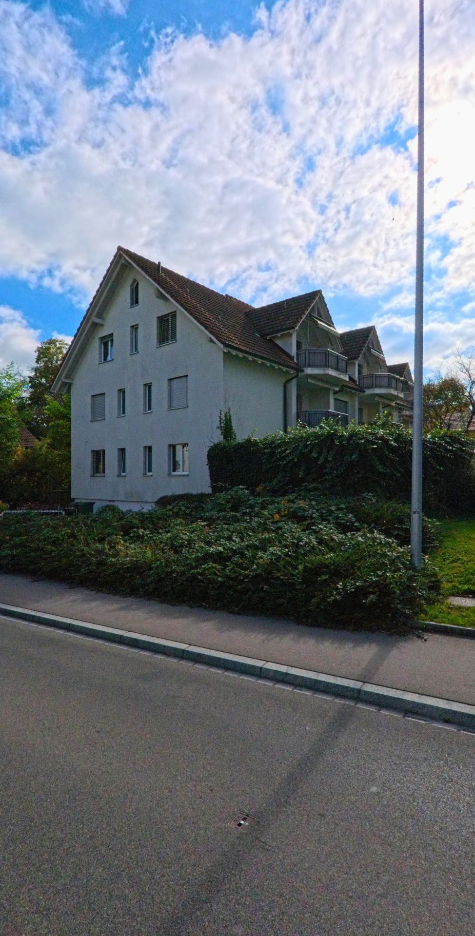 Hinter einer niedrigen Hecke steht in Wagenhausen (8259, Kanton Thurgau) ein Mehrfamilienhaus mit Balkonen entlang einer ruhigen Quartierstrasse.
