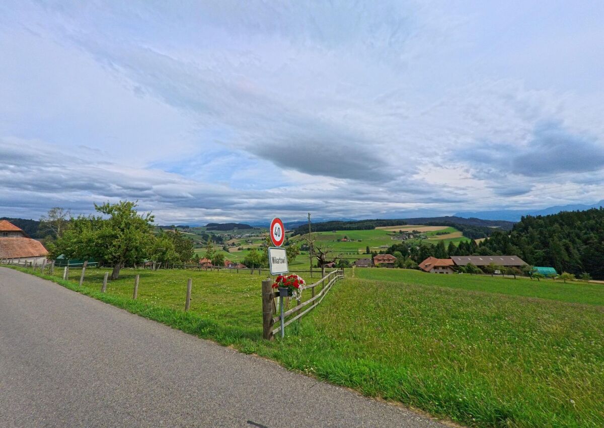 Am Ortseingang von Walkringen (3077, Kanton Bern) blickt man auf verstreute Bauernhöfe inmitten einer sanft hügeligen Landschaft.