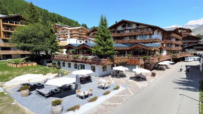 Das Walliserhof Grand-Hotel & Spa in Saas-Fee (3906, Kanton Wallis) kombiniert traditionelle Holzarchitektur mit modernen Elementen und bietet eine sonnige Terrasse mit Sitzplätzen.