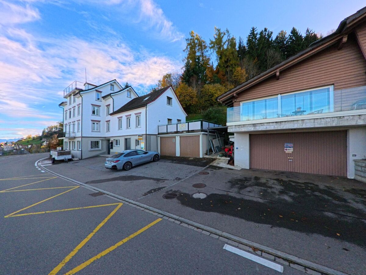 In Walzenhausen (9428, Kanton Appenzell Ausserrhoden) saeumen ein mehrgeschossiges Wohnhaus und ein Gebaeude mit grosser Terrasse die leicht abfallende Strasse am Hang.
