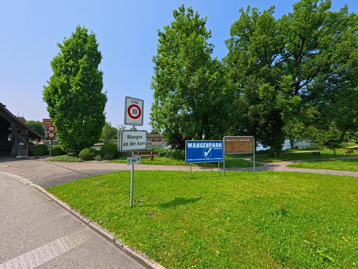 Beim Ortseingang von Wangen an der Aare (3380, Kanton Bern) markieren mehrere Schilder die Tempo-30-Zone und weisen auf den angrenzenden Park am Fluss hin.