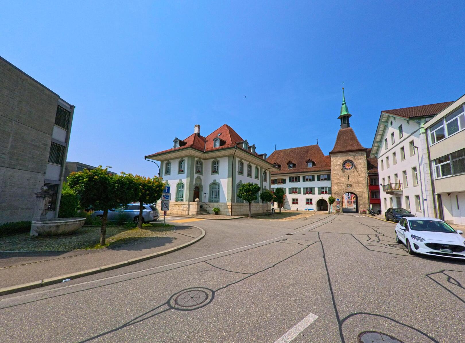 Im Zentrum von Wangen an der Aare (3380, Kanton Bern) steht das markante Stadttor mit Uhrturm, flankiert von historischen Gebäuden und einem kleinen Platz.