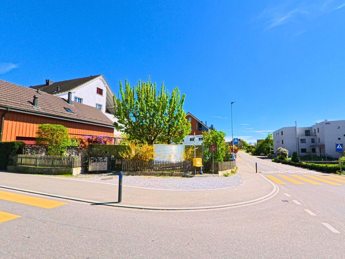 In Wangen-Brüttisellen (8602, Kanton Zürich) liegt ein gut einsehbarer Strassenabschnitt mit Zebrastreifen zwischen modernen Wohnhäusern und gepflegten Gärten.