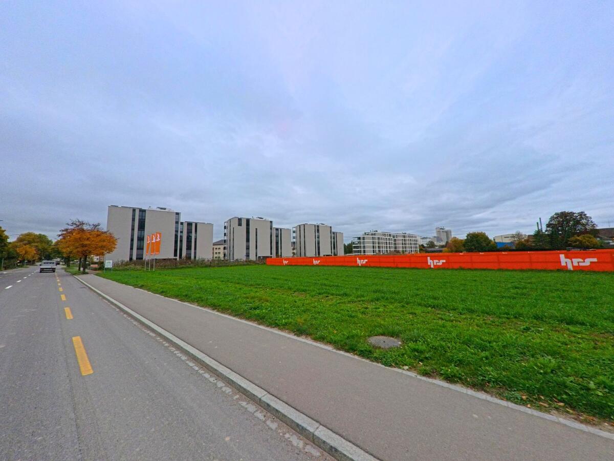 Neben einer breiten Grünfläche erstrecken sich moderne Wohnbauten entlang einer Quartierstrasse in Weinfelden (8570, Kanton Thurgau).