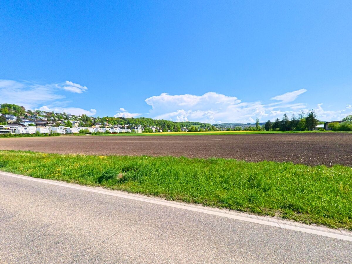 In Wettswil am Albis (8907, Kanton Zürich) erstreckt sich ein frisch bestellter Acker vor einer modernen Wohnsiedlung am sanft ansteigenden Hang.