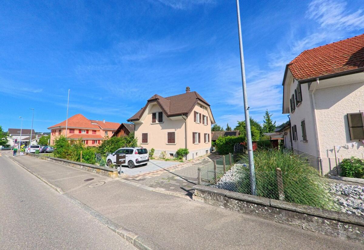 Entlang einer ruhigen Strasse in Wikon (4806, Kanton Luzern) reihen sich gepflegte Einfamilienhaeuser mit Vorgarten und gepflasterter Einfahrt aneinander.