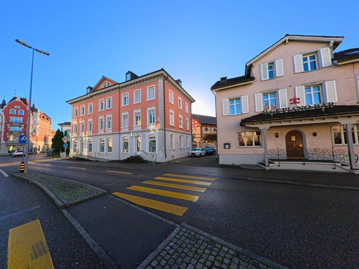 Entlang eines Zebrastreifens stehen gepflegte Wohn und Geschaeftshaeuser an einer Kreuzung im Stadtgebiet von Wil (9500, Kanton St. Gallen) bei ruhiger Verkehrslage.
