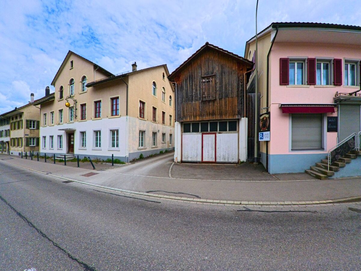 In Wila (8492, Kanton Zürich) führt die Strasse an historischen Gebäuden entlang, darunter ein altes Holzhaus und ein restauriertes Gebäude.