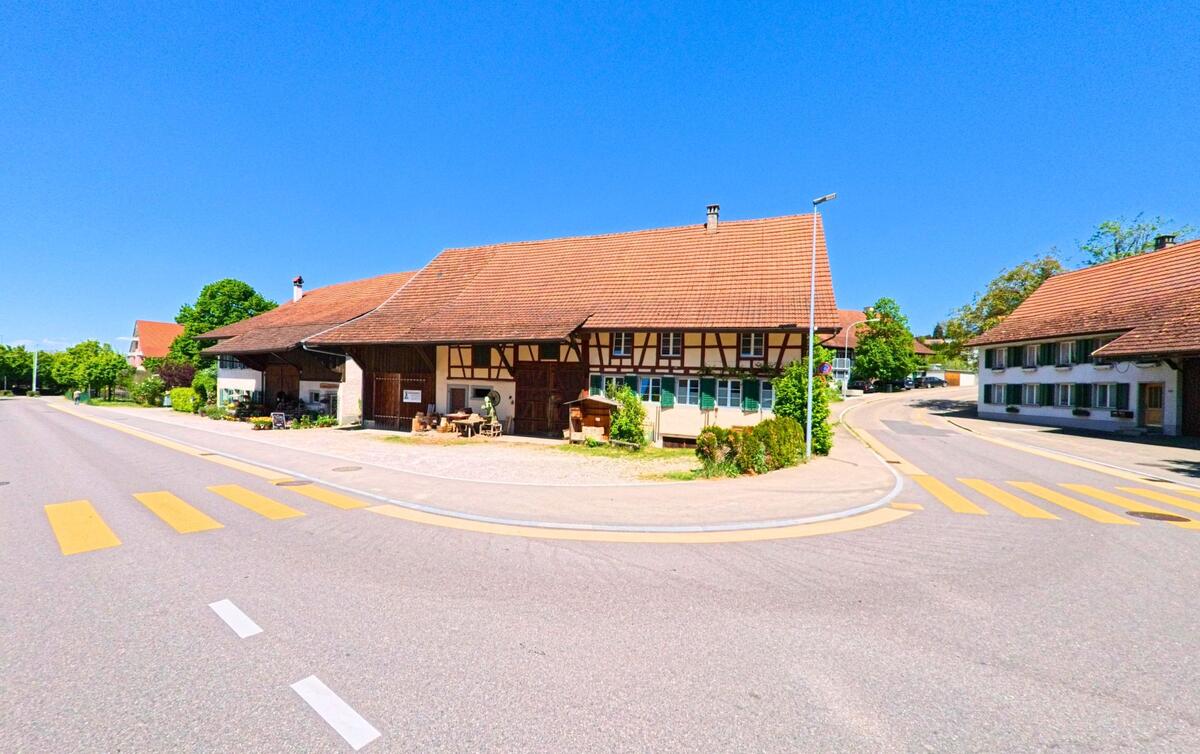 Ein traditionelles Bauernhaus mit Fachwerk und grosszügigem Vorplatz steht in einer Kurve in Winkel, PLZ 8185 im Kanton Zürich, an einer ruhig gelegenen Kreuzung.