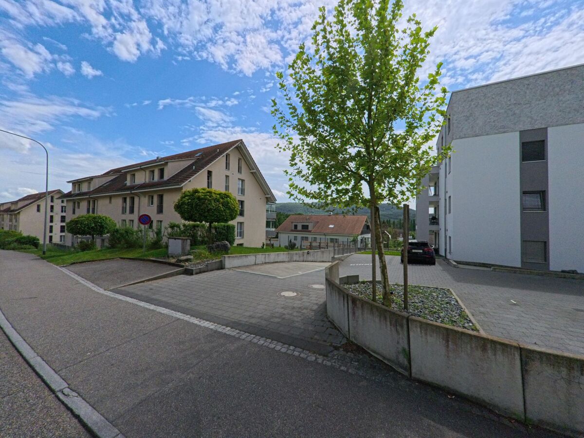 Zwischen modernen Mehrfamilienhäusern in Winznau (4652, Kanton Solothurn) verläuft eine ruhige Quartierstrasse mit jungen Bäumen und gepflegten Vorplätzen.