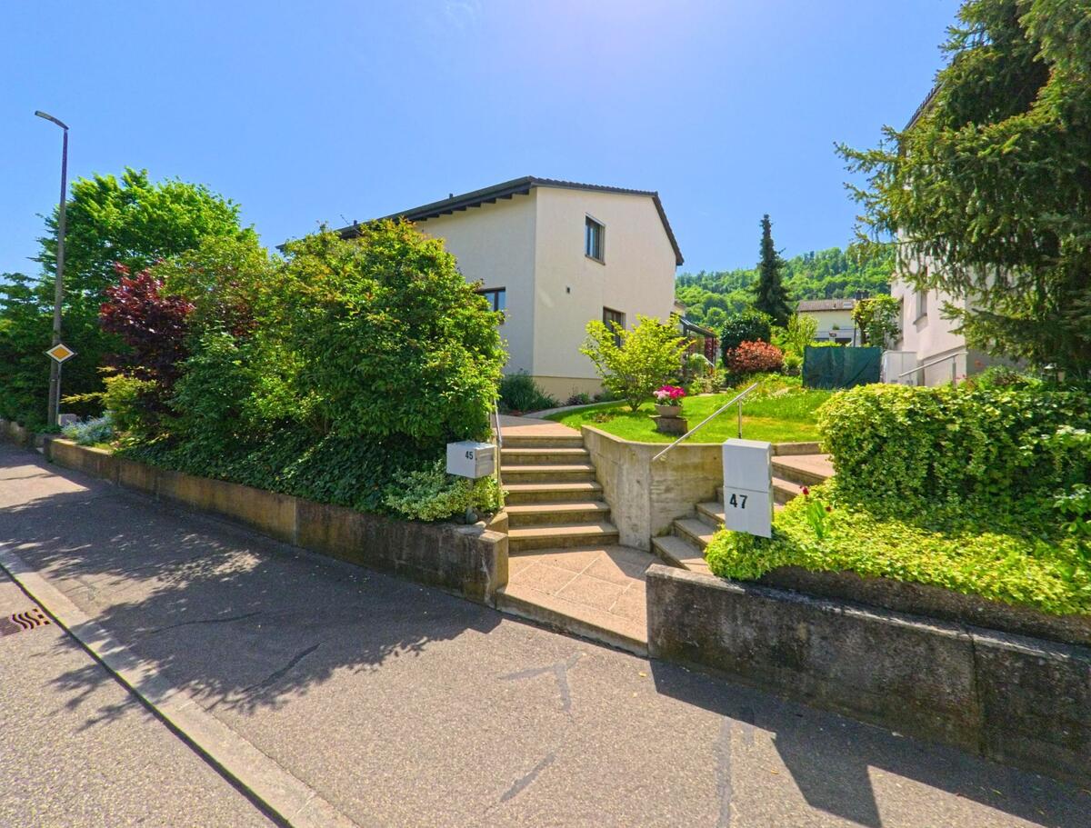 In Witterswil (4108, Kanton Solothurn) führen symmetrisch angelegte Treppen zu zwei gepflegten Einfamilienhäusern mit üppiger Gartengestaltung.