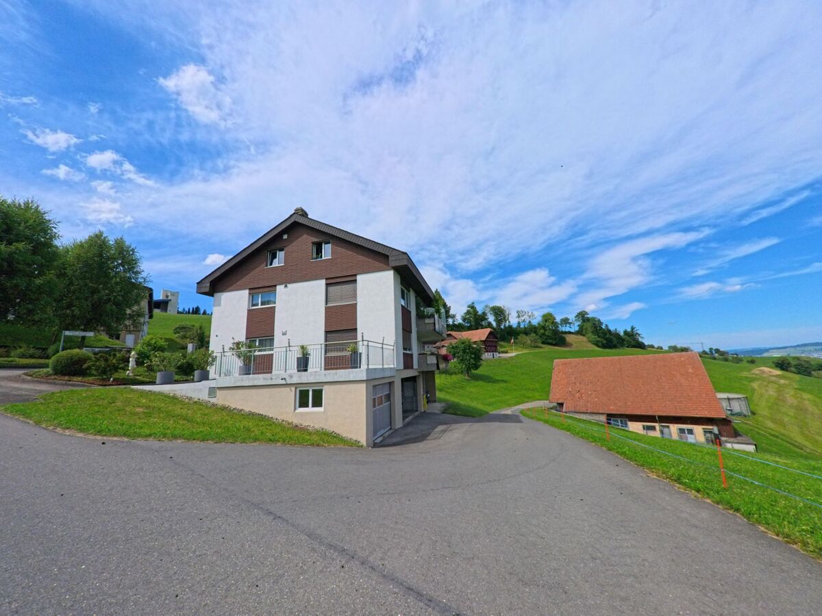 Ein Wohnhaus am Hang in Wolhusen (6110, Kanton Luzern) bietet Aussicht über grüne Wiesen und verstreute Bauernhäuser in der hügeligen Landschaft.