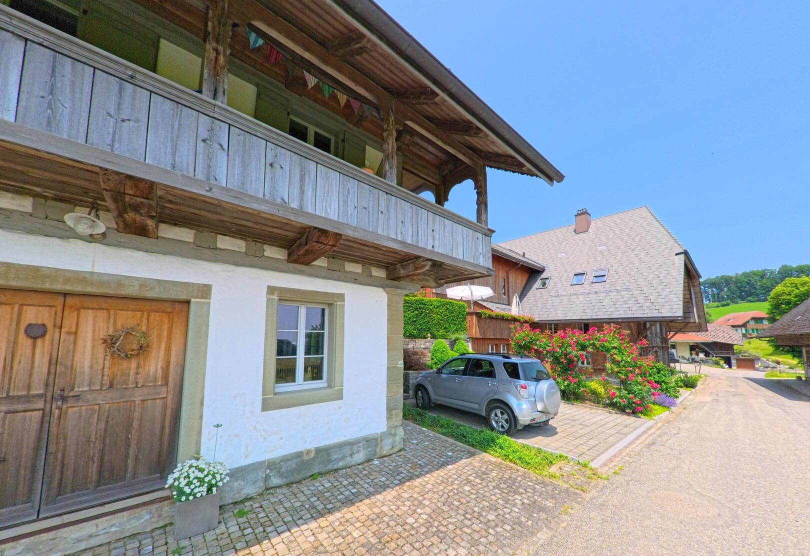 In Wynigen (3474, Kanton Bern) reihen sich gepflegte Wohnhäuser mit Blumenschmuck und Holzfassaden entlang einer ruhigen Quartierstrasse.