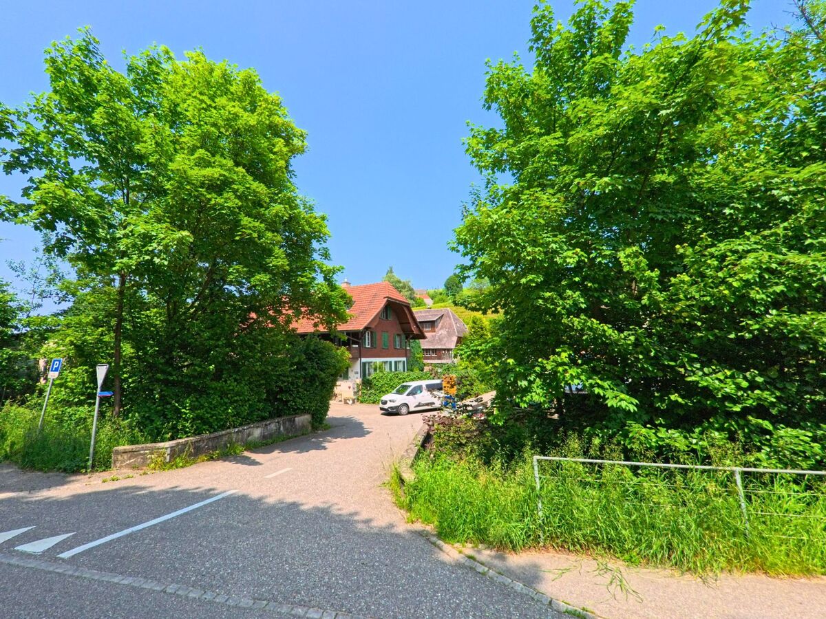 Ein von Baeumen umgebenes Wohnhaus mit gruenen Fensterlaeden liegt in Wyssachen (4954, Kanton Bern) ruhig am Ende einer kleinen Seitenstrasse.