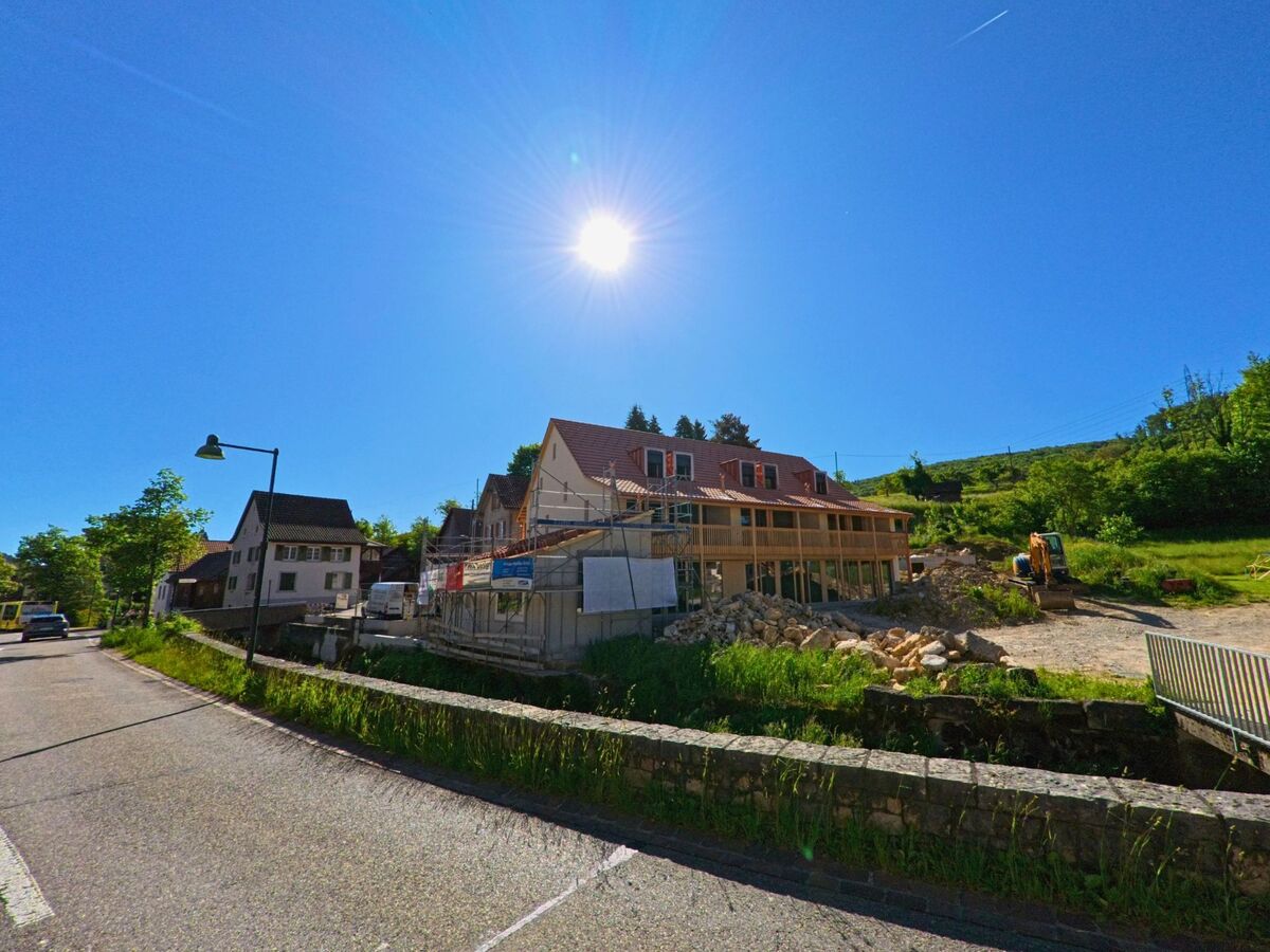 In Ziefen (4417, Kanton Basel-Landschaft) entsteht am sonnigen Hang ein Neubau, eingerahmt von bestehender Wohnbebauung und grüner Landschaft.
