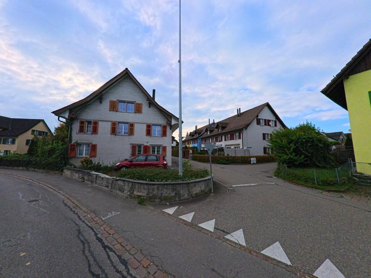 An einer kleinen Strassenkreuzung in Zihlschlacht-Sitterdorf (8588, Kanton Thurgau) stehen Wohnhäuser mit Fensterläden, umgeben von ruhigen Quartierstrassen und Gärten.