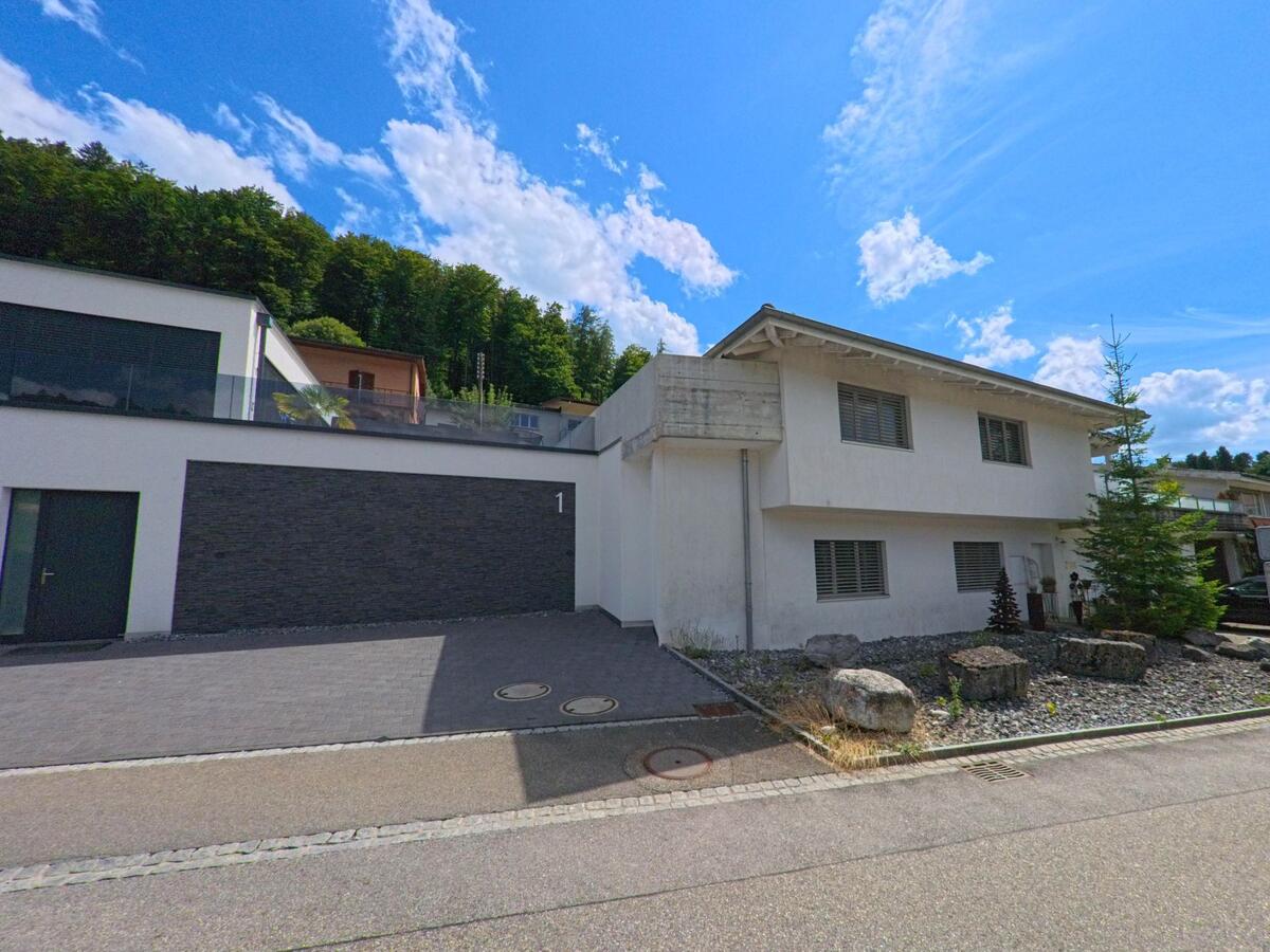 In einem Wohnquartier von Zofingen (4812, Kanton Aargau) steht ein modernes Einfamilienhaus mit steingefasstem Vorgarten und gepflasterter Garagenzufahrt.
