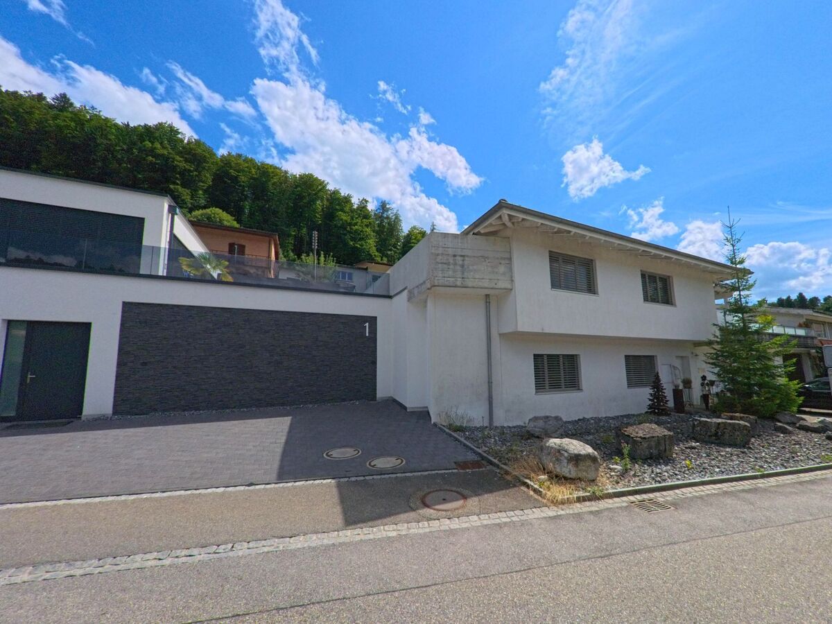 In einem Wohnquartier von Zofingen (4812, Kanton Aargau) steht ein modernes Einfamilienhaus mit steingefaßtem Vorgarten und gepflasterter Garagenzufahrt.