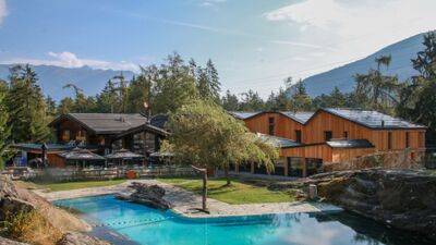Beim Zoo des Marécottes in Les Marécottes (1923, Kanton Wallis) liegt ein Freibad mit klarem Wasser und Holzgebäuden inmitten von Bäumen und Bergen.