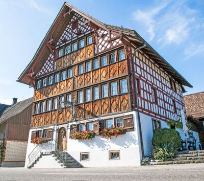 In Niederbueren (9246, Kanton St. Gallen) steht das historische Gasthaus Zur alten Herberge mit markanter Fachwerkfassade und Blumenschmuck an den Fenstern.