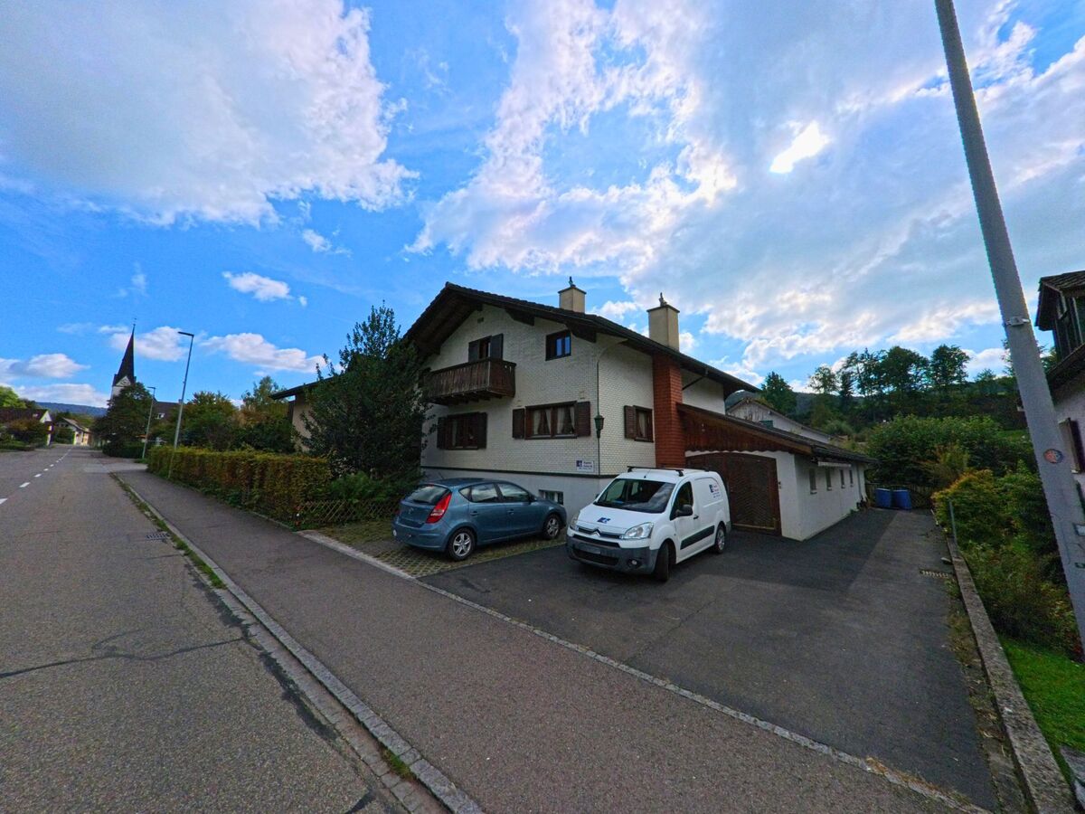 In Zuzgen (4315, Kanton Aargau) stehen gepflegte Wohnhaeuser mit Balkon entlang einer ruhigen Strasse, vor denen mehrere Fahrzeuge parken.